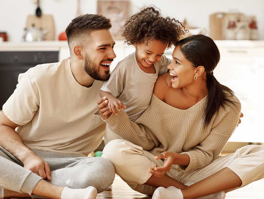 A family sitting the floor laughing with a toddler